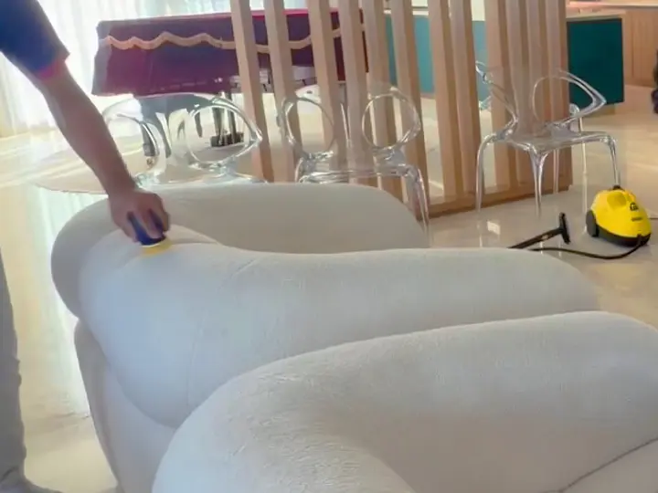 TopOne cleaner treating a white sofa with a hand tool