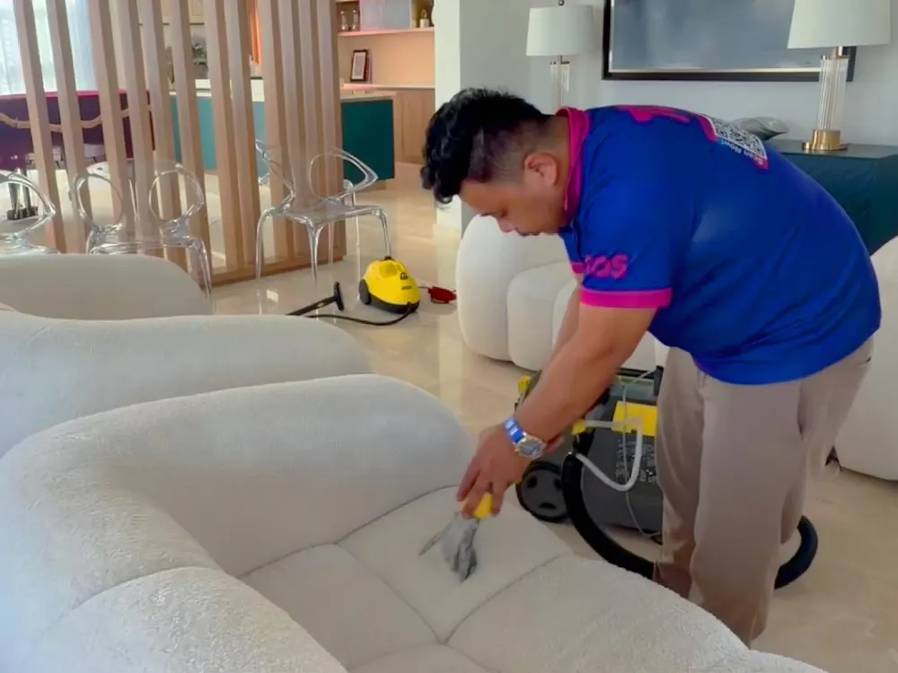 A TopOne cleaner treating a white fabric sofa with a steam and extraction tool