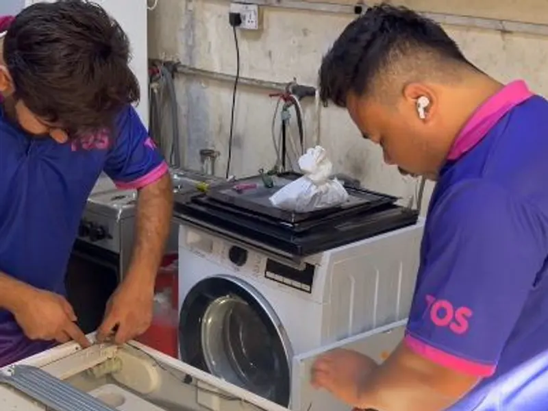 Two TopOne technicians repairing a washing machine